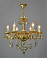 Šestiramenný lustr z pokoveného křišťálu v jantarovém odstínu na světlém pozadí osvětlený